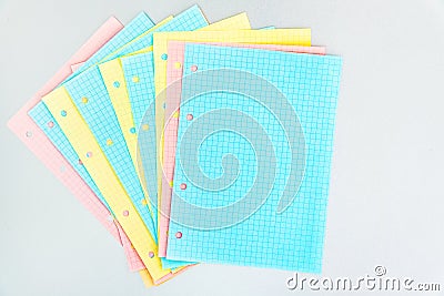 Blank checkered pages from a folding notebook in different pastel colors scattered on silver desk Stock Photo