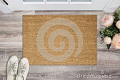 Blank coir doormat before the door in the hall. Mat on wooden floor, flowers and shoes. Welcome home, product Mockup Stock Photo