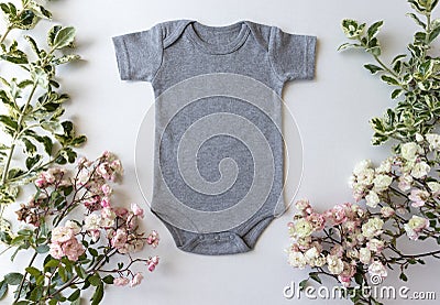 Blank Gray Baby Grow On An Off White Background With Green Leaves and Pink Roses Stock Photo