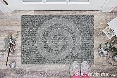 Blank grey doormat before the door in the hall. Mat on wooden floor, with christmas decoration and slippers. Welcome Stock Photo