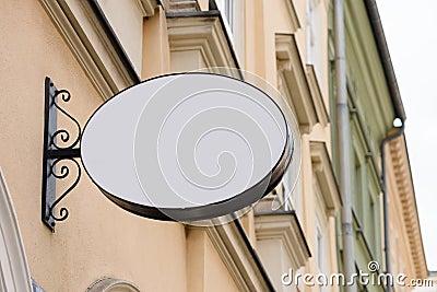 Blank metal oval store signboard on street hanging mounted on the wall Stock Photo