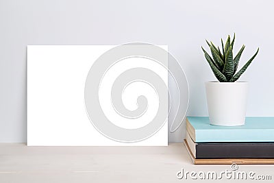 Blank mockup paper sheet copy space and plants in potted on book on wooden table. Stock Photo