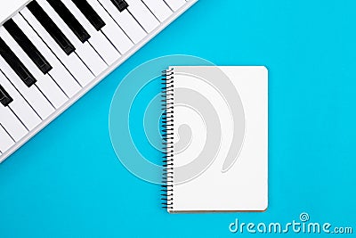 Blank notebook and piano on a blue background, flat lay, copy space. Stock Photo