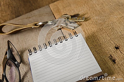 Blank notepad, key chain and eye glasses on wooden table Stock Photo