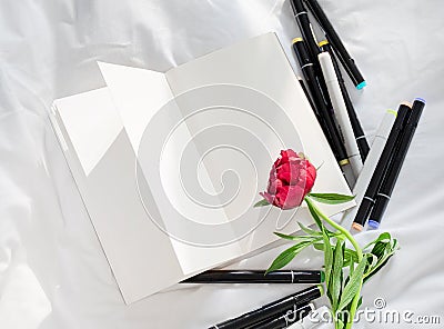 Blank open diary on a white bed with pile of pens Stock Photo