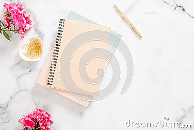 Blank paper notebook, pink flowers, golden stationery on marble background. Flat lay, top view feminine home office desk Stock Photo
