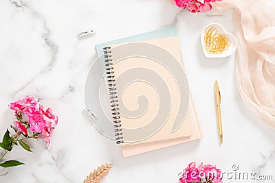 Blank paper notebook, pink flowers, pastel blanket and golden accessories on marble background. Flat lay, top view rose gold home Stock Photo