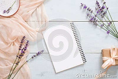 Blank paper notepad, pastel pink color blanket, lavender flowers and gift box on rustic blue wooden background. Top view, tender Stock Photo