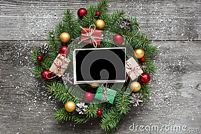 Blank photo frame in christmas wreath with decorations and gift boxes on rustic wooden table Stock Photo