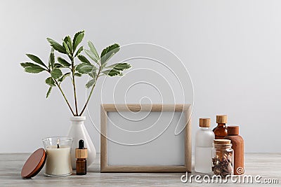 Blank photo frame, different bottles and decor elements on wooden table Stock Photo