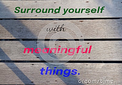 Inspirational quote - Surround yourself with meaningful things. A sign on a rustic wooden wall with colorful text message. Stock Photo