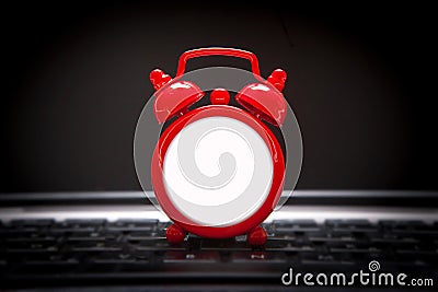 Blank red alarm clock lies on the laptop keyboard Stock Photo