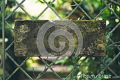 Blank rustic wooden sign hung on a steel fence. Stock Photo