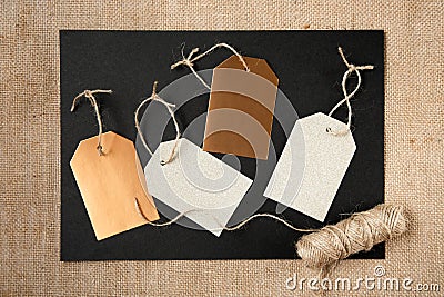 A blank sheet of black paper with gift tags are on a canvas background. Decoration of Christmas gifts and seasonal sale. Stock Photo