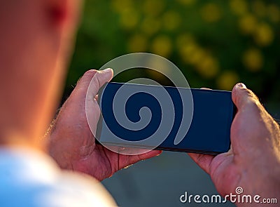 Mock up man using smartphone blank display mobile phone background. Caucasian man watching smartphone screen holding on horizontal Editorial Stock Photo