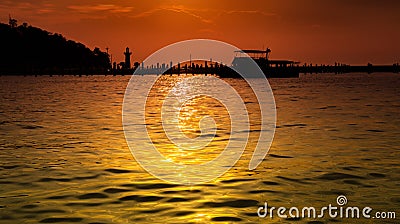 Blank space on the water surface of the sea, golden light and orange light, the background of silhouette pier and boat. Enhance Stock Photo