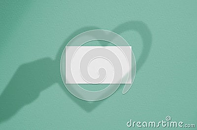 Blank white business card with hand and heart shadow overlay. Modern and stylish brand card mock up. Stock Photo