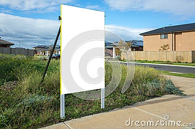 Blank white empty mockup template of a real estate sign at front of a lot of vacant land in a suburban neighbourhood Stock Photo