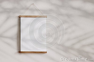 Blank wooden picture frame hanging on beige wall. Empty poster mockup for art display in sunlight. Minimal interior Stock Photo