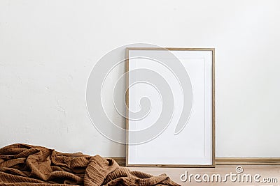 Blank wooden vertical picture frame mock-up on floor. Cinnamon linen plaid. White wall background. Empty copy space, no Stock Photo