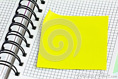 Blank yellow stick note on a spiral notebook from above. Removable self-stick notes. Stock Photo