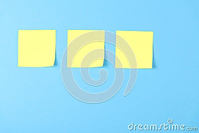 Blank yellow sticky notes on a blue background, concept of business work. Yellow memo stickers on blue wall. Mock-up Stock Photo