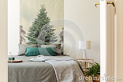 Blanket on grey bed in hotel bedroom interior with tree painting Stock Photo