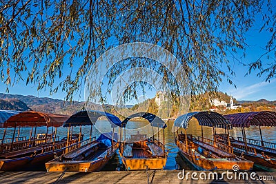 Bled, Slovenia - Traditional red, orange and blue Pletna boats in the autumn sunshine at Lake Bled Stock Photo