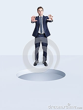 Blindfolded businessman and big hole in the ground in front of him Stock Photo