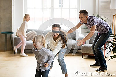 Blindfolded mother catching son playing hide and seek with famil Stock Photo