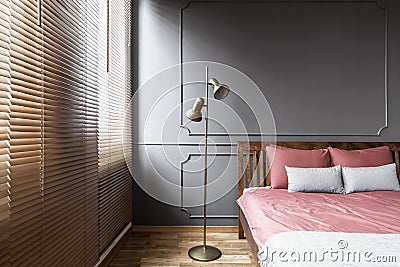 Blinds and golden lamp in dark and elegant bedroom interior with Stock Photo