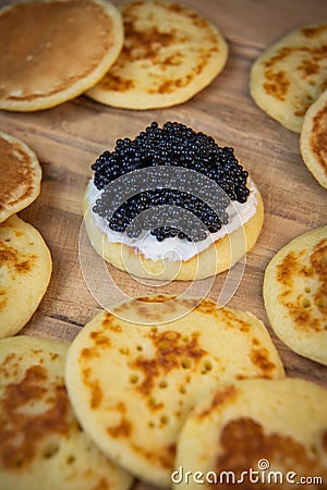 Blinis with black caviar and cream cheese, on a festive dish, mini pancakes, an elegant appetizer Stock Photo