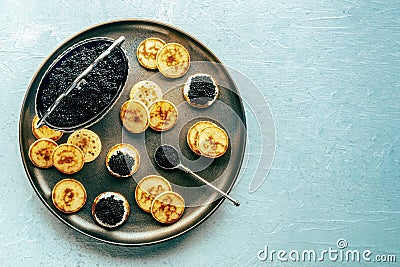 Blinis with black caviar and cream cheese, overhead flat lay shot Stock Photo