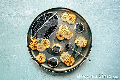 Blinis with black caviar and cream cheese, overhead flat lay shot Stock Photo