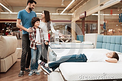 Blissful family buys new orthopedic mattress in furniture store. Happy family choosing mattresses in store. Stock Photo