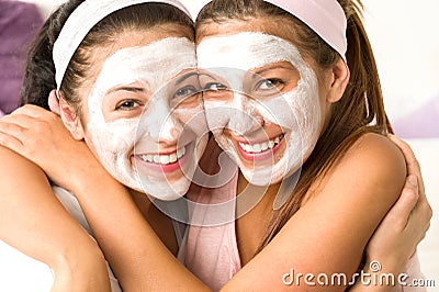 Blissful girls applying mask hugging each other Stock Photo