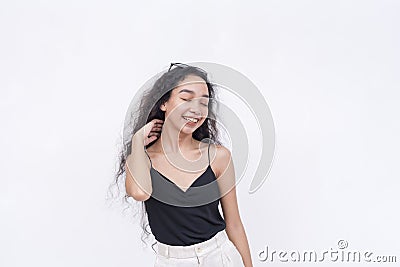 A blissful young asian with a radiant smile closes her eyes while enjoying the moment. on a white backdrop Stock Photo
