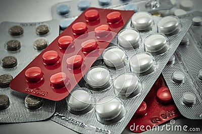 Blisters with round multi-colored tablets red yellow blue white on a light background close-up, antibiotics, vitamins, analgesic a Stock Photo