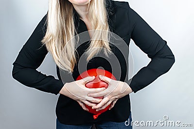 Bloating and flatulence concept. The woman holds a red balloon near the abdomen, which symbolizes bloating. Intestinal tract and d Stock Photo