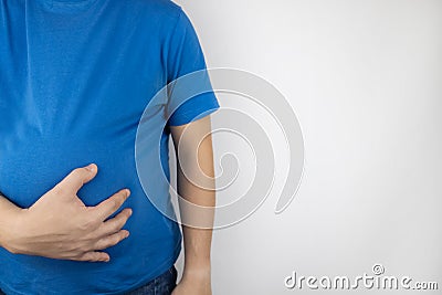 The man is holding onto his swollen belly. Bloating, flatulence, gas, malfunction of the gastrointestinal tract. Bending over in Stock Photo