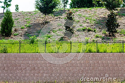 Block Retaining Wall Topped with Black Iron Fence Stock Photo