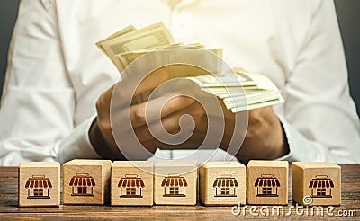 Blocks symbolizing business network and businessman counting money. High income from commercial real estate rent. Taxes payment. Stock Photo