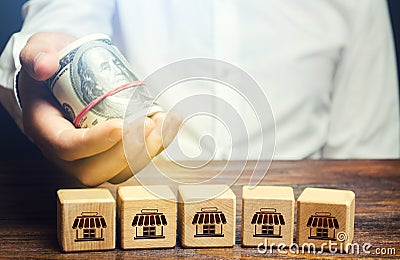 Blocks symbolizing business network and businessman holds out money. Offer for purchase of a business. Merge small competitors Stock Photo