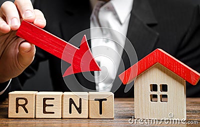 Blocks with the word Rent, down arrow and a miniature house. The concept of reducing the price of renting a house or apartment. Stock Photo