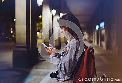 Blogger hipster using in hands gadget mobile phone, woman with backpack pointing finger on blank screen smartphone on background b Stock Photo