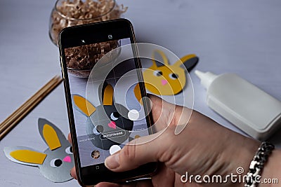 a blogger takes photos of the process of making Easter bunnies on his phone Stock Photo