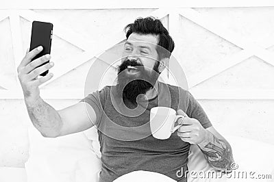 Blogging from bed. Happy blogger drink coffee in morning. Bearded man keep real time live blog. Keeping private personal Stock Photo