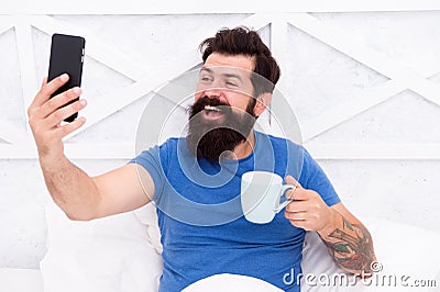 Blogging from bed. Happy blogger drink coffee in morning. Bearded man keep real time live blog. Keeping private personal Stock Photo