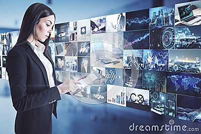 Blogging and content creation concept with woman in black suit working on digital tablet and video archive wall Stock Photo