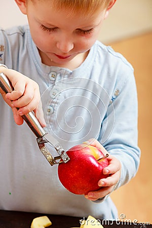 Blond boy child kid preschooler peelings fruit apple at home Stock Photo